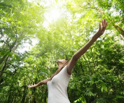 Frau mit offenen Armen im Wald