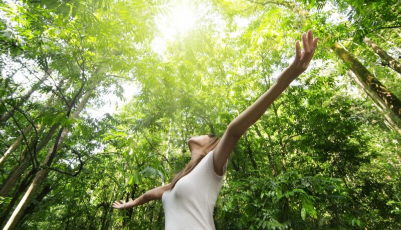 Frau mit offenen Armen im Wald